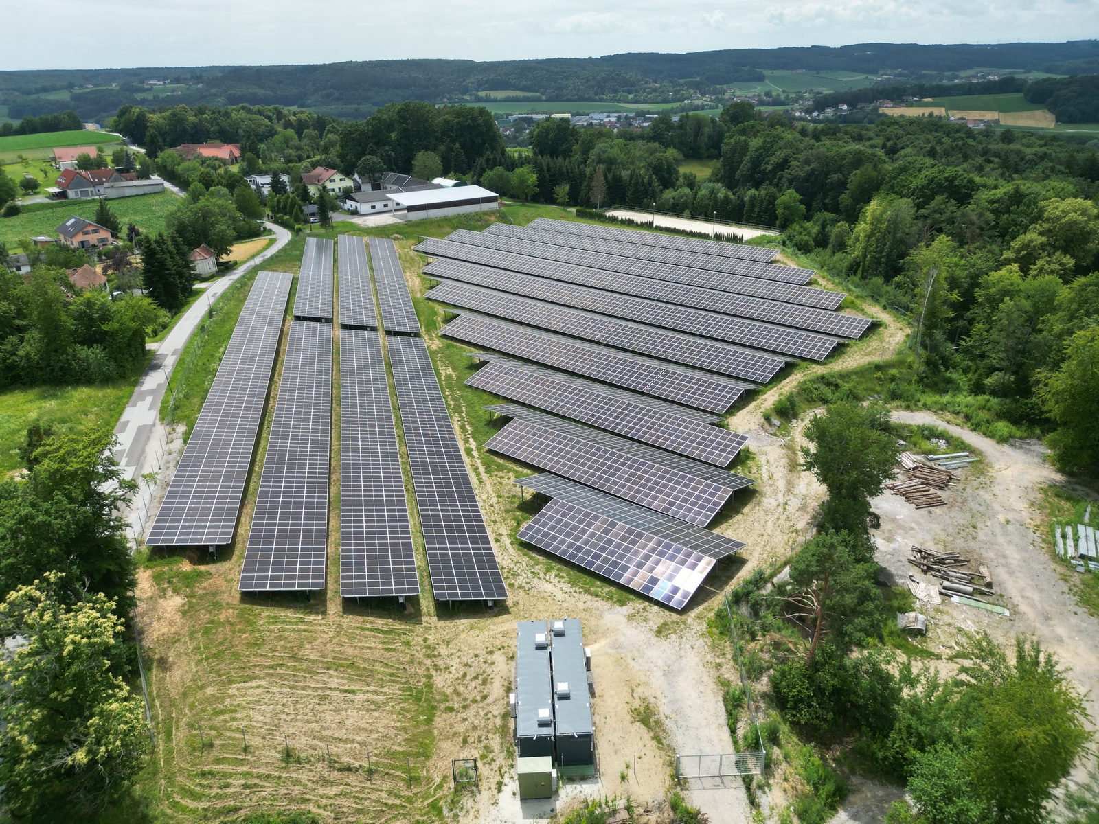 Drohnenaufnahme des fertigen PV-Parks Sebersdorf am Hang, eingebettet in die steirische Hügellandschaft, mit Trafostation